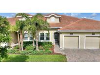Charming home featuring a red tile roof, a two-car garage and palm trees accenting the landscaped front yard at 1064 Quaker Ridge Ln, Davenport, FL 33896