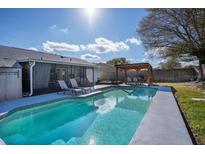 Inviting backyard pool with lounge chairs, outdoor dining under pergola, and well-maintained landscaping at 1375 Springfield St, Kissimmee, FL 34744