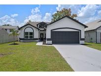Charming single-story home with a two-car garage, well-manicured lawn, and black and white color scheme at 14639 Musket Fire Ln, Orlando, FL 32837