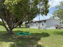 Manufactured home with a brown and gray exterior, set in a large lot with a tree swing at 15311 Johns Lake Rd, Clermont, FL 34711
