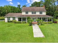 Charming two-story home featuring a welcoming front porch, lush lawn, and mature trees at 2471 Jenscot Rd, St Cloud, FL 34771
