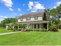 Charming two-story home featuring a welcoming front porch, lush lawn, and manicured landscaping at 2471 Jenscot Rd, St Cloud, FL 34771