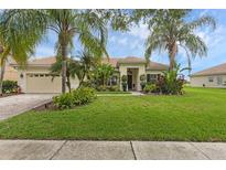 Charming single-story home with lush tropical landscaping, palm trees, and a well-manicured lawn at 3617 Northwoods Dr, Kissimmee, FL 34746