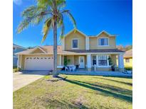 Charming two-story home with well-maintained landscaping, mature palm tree, and inviting front porch at 416 Sea Willow Dr, Kissimmee, FL 34743