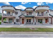 Inviting townhome featuring dual balconies, stone accents and an orange front door with a wreath at 5103 Jones Rd, St Cloud, FL 34771