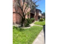 Charming exterior view of townhomes with brick and wood, mature landscaping, and manicured lawn on a sunny day at 5144 Picadilly Circus Ct # 2, Orlando, FL 32839