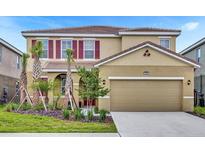 Charming two-story home featuring a well-manicured lawn, beautiful landscaping, and a two-car garage at 7622 Oakmoss Loop, Davenport, FL 33837