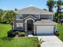 Charming two-story home featuring a well-manicured lawn, mature trees, and an attached two-car garage at 8491 Oasis Key Cv, Kissimmee, FL 34747