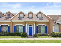Charming townhome featuring a blue door, blue shutters, and manicured landscaping at 2050 Island Walk Dr, Orlando, FL 32824