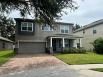 Two-story home with a two-car garage, paver driveway, and a welcoming front porch at 2813 Roseglen Way, Orlando, FL 32812
