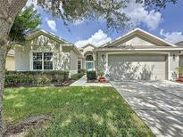 Charming single-story home with a manicured lawn, blue front door, and two-car garage at 2924 White Cedar Cir, Kissimmee, FL 34741
