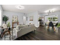 Open-concept living room flows to dining area, showcasing modern lighting and sleek, dark wood flooring at 410 Kentia Rd, Casselberry, FL 32707