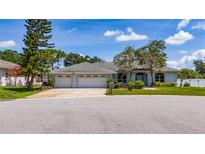 Charming single-story home with a three-car garage, mature trees, and well-maintained landscaping on a sunny day at 415 Smiley Ct, Winter Haven, FL 33884