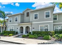 Inviting gray two-story townhome with neatly manicured landscaping, and white trim against a beautiful blue sky at 4981 Windermere Ave, Kissimmee, FL 34746