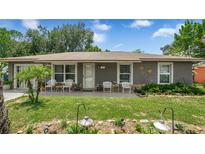 Charming single-story home featuring a well-manicured lawn and cozy front porch with seating at 505 Oak Dr, Tavares, FL 32778