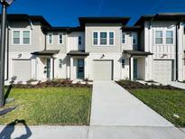 Charming townhome exteriors with light neutral colors, well-manicured lawns, and attached garages at 775 Longboat Dr, Davenport, FL 33896