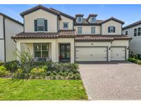 Charming two-story home with lush landscaping, a tile roof, and a three-car garage at 9071 Woodland Forest Rd, Orlando, FL 32836