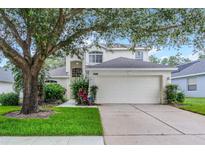 Charming two-story home with a two-car garage, landscaped yard, and mature trees at 909 Troon Cir, Davenport, FL 33897