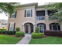 Two-story condo with a beige stucco exterior, brown shutters, manicured landscaping, and covered porches at 14205 Falls Church Dr # 2012, Orlando, FL 32837