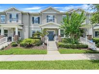 Charming townhome featuring a covered porch, landscaped yard, and a stylish blue front door at 15540 Blackbead St, Winter Garden, FL 34787