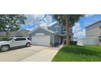 Two-story home featuring a two car garage, palm tree, and manicured front yard at 1827 Meadow Pond Way, Orlando, FL 32824