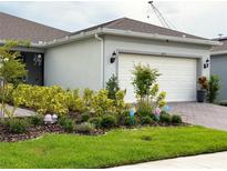 Charming home featuring a well-manicured front yard with colorful landscaping and an attached two-car garage at 1875 Spring Shower Cir, Kissimmee, FL 34744