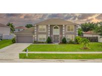 Charming two-story home with a manicured front yard, beautiful landscaping, and an attached two-car garage at 1912 Maury Rd, St Cloud, FL 34771