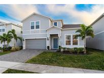 Charming two-story home with a manicured lawn, a paved driveway, and decorative palm trees at 2161 Lelani Cir, Davenport, FL 33897