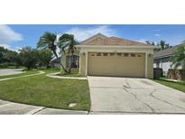 Inviting single-story home with a two-car garage, lush lawn, and mature palm trees at 2401 Cedarfield Ln, Kissimmee, FL 34744