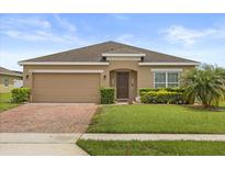 Charming single-story home with a well-manicured lawn, a brick driveway, and a two-car garage at 3797 Briarwood Estates Cir, St Cloud, FL 34772