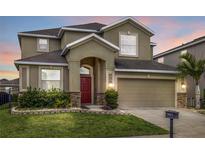 Charming two-story home featuring a two-car garage, red door, and well-maintained landscaping at 3853 Cortland Dr, Davenport, FL 33837