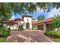 Stunning Mediterranean-style home featuring a terracotta tile roof and lush landscaping at 4224 Clarice Estates Dr, Windermere, FL 34786