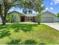 Charming single-story home with a well-manicured lawn, mature trees, and an attached two-car garage at 4607 Pine Lake Dr, St Cloud, FL 34769