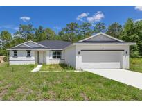 Charming single-story home with a two-car garage, white exterior, and a well-manicured front lawn at 7 Spring Pass, Ocala, FL 34472