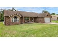 Charming brick home featuring a well-manicured lawn and a cozy front porch with seating at 1063 Fountainhead Dr, Deltona, FL 32725