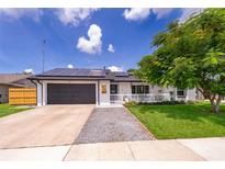 Charming single-story home featuring a gray-tone front door, gray-tone garage, solar panels, and well-maintained landscaping at 12104 Shallot St, Orlando, FL 32837
