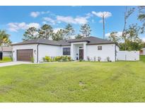 Well-manicured lawn and landscaped garden beds accent this charming, white single-story home at 2668 Coachman Dr, Deltona, FL 32738