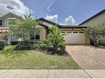 Charming single-story home with brick driveway, lush landscaping, and an attached two-car garage at 3193 Crispin Cir, Harmony, FL 34773