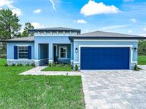Beautiful single-story home with a well-manicured lawn, paved driveway, and attractive blue garage door and shutters at 41 Orchid Ct, Kissimmee, FL 34759
