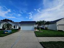 Charming single-story home featuring a two-car garage, well-manicured lawn, and swaying palm trees at 5661 Parkview Lake Dr, Orlando, FL 32821