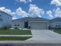 Beautiful single-story home featuring a gray exterior, a two-car garage, and manicured landscaping at 568 Meadow Bend Dr, Davenport, FL 33837