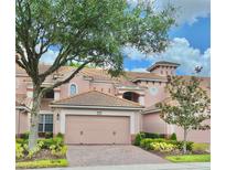 Charming pink two-story home featuring a tile roof, brick driveway, and well-maintained landscaping at 8401 Riverdale Ln # 8401, Davenport, FL 33896
