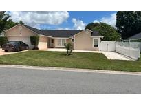 Tan home with a two car garage, manicured lawn, and lovely landscaping at 112 Rosewood Ct, Kissimmee, FL 34743