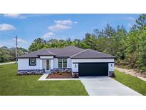 Beautiful new home with black trim, stone accents, well manicured lawn, and 2-car garage at 14967 Sw 43Rd St, Ocala, FL 34473