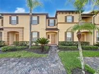 Charming townhome featuring lush landscaping, a brick walkway, and decorative shutters at 226 Verona Ave, Davenport, FL 33897