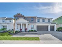 Charming three-story home showcasing manicured landscaping, a three-car garage, and a paved driveway at 2525 Shanti Dr, Kissimmee, FL 34746