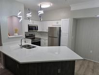 Bright kitchen boasts white cabinetry, stainless steel appliances, and quartz countertops with a central island at 3428 Soho St # 208, Orlando, FL 32835