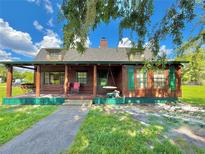 Charming log cabin exterior featuring a covered porch, swing, and beautiful yard at 4075 Packard Ave, St Cloud, FL 34772