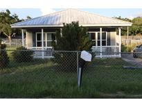 Charming single-story home featuring a white picket fence and a well-manicured lawn with mature trees at 423 Midway Ave, Mascotte, FL 34753