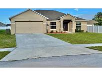 Inviting single-Gathering home boasts a well-manicured lawn, two car garage, and neatly landscaped garden beds at 841 Fir Ave, Frostproof, FL 33843